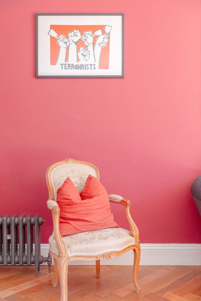 An armchair in the living room of an Airbnb house, pink walls.