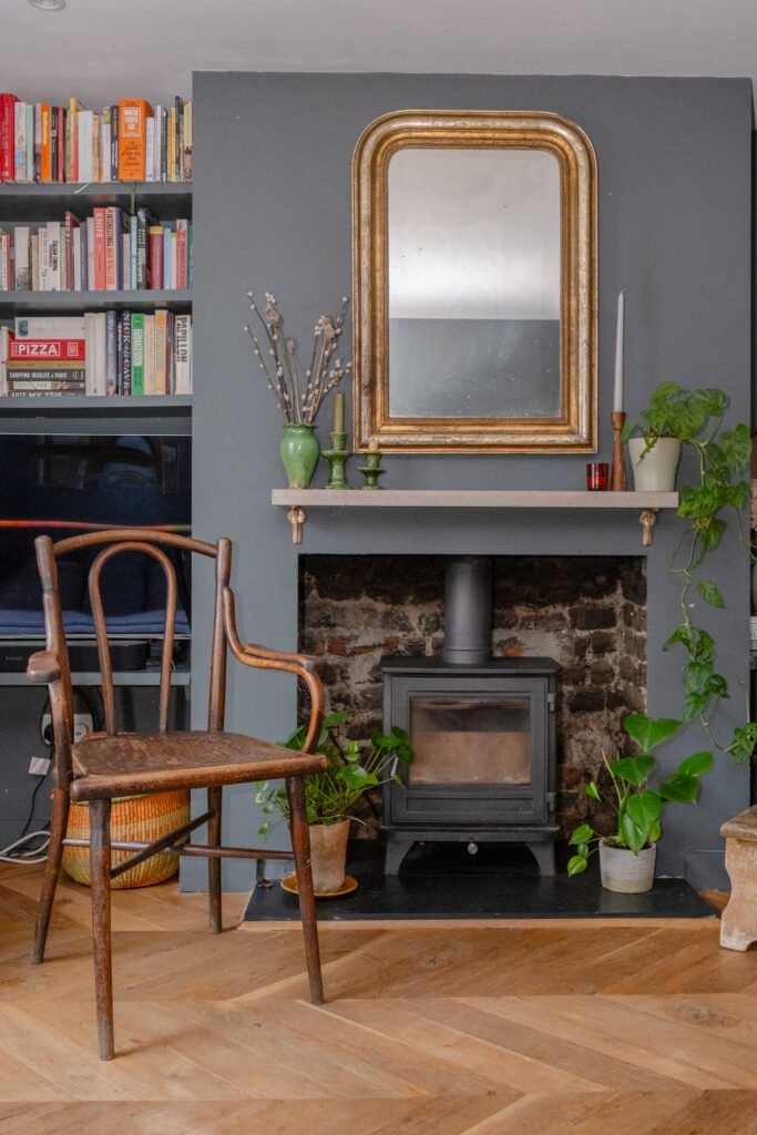 A wooden chair in front of a decorative fireplace
