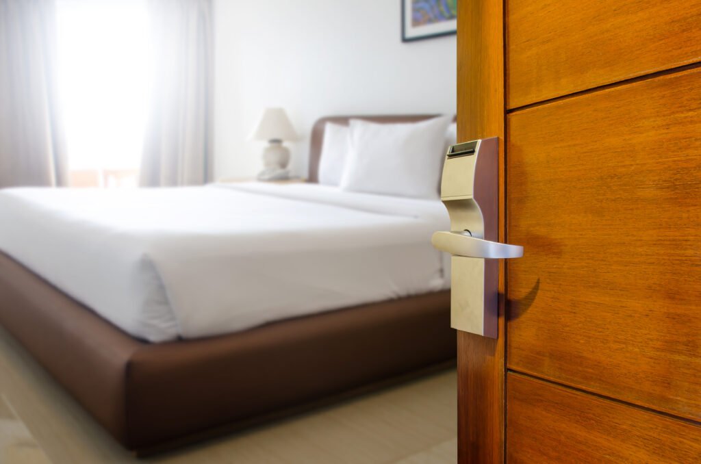 Hotel room door semi open, showing the bed inside, modern design.