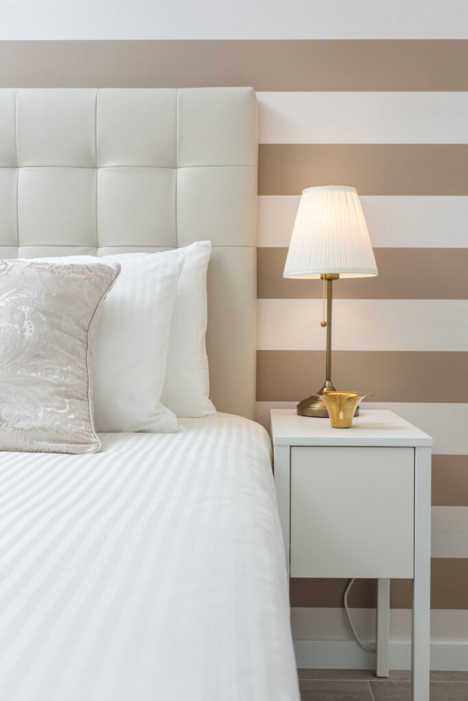 White headboard and a bed with white sheets, partial vertical image.